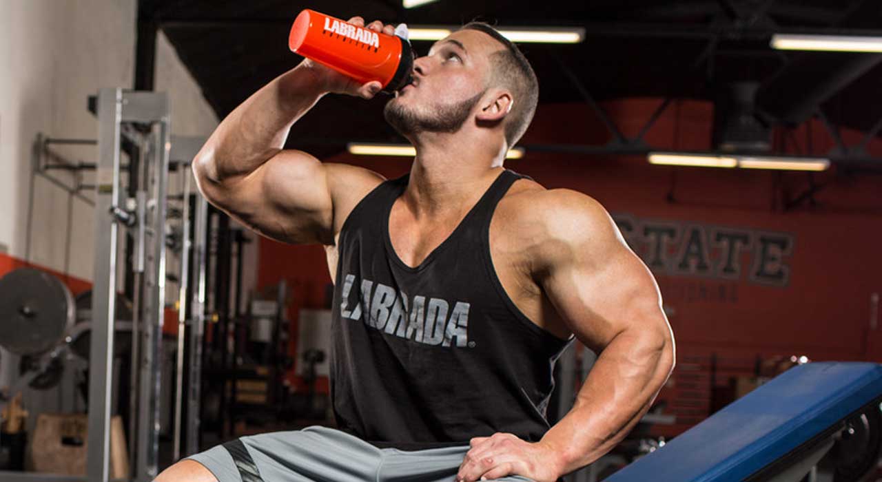 muscular man in the gym drinking from a protein shaker