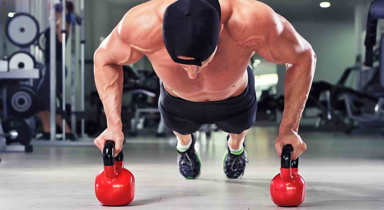man with cap on working out with two kettlebells