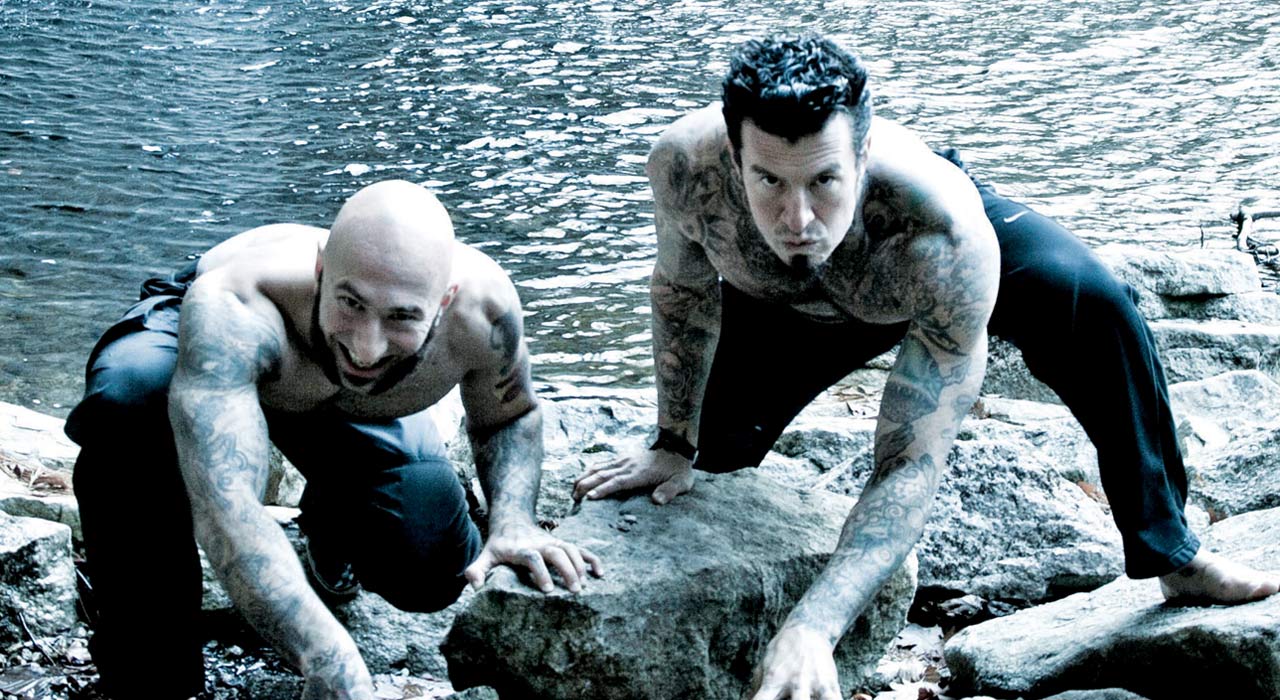 the kavaldo brothers kneeling down on rocks in front of some water