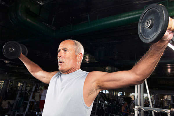 older man in the gym performing a lateral raise
