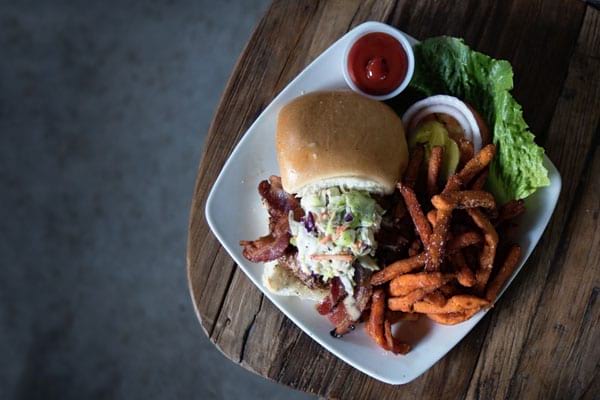 burger chips coleslaw lettuce and tomato sauce on a plate