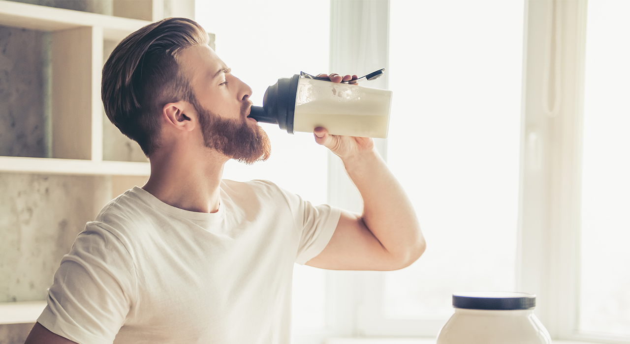 man drinking from a protein shaker