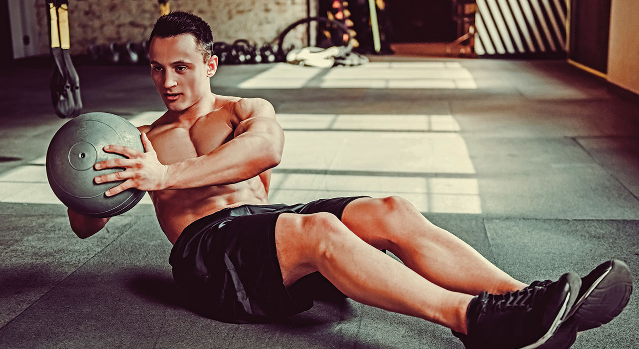 muscular man performing russian twists in a workout studio