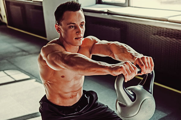 muscular man performing a squat with a kettlebell in a workout studio