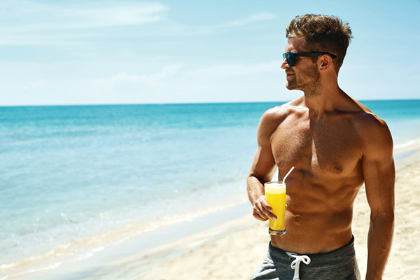 man on the beach with a cocktail in hand