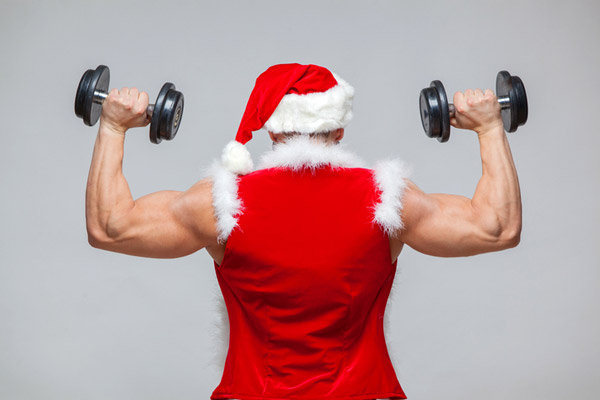 muscular man in santa suit performing standing shoulder press