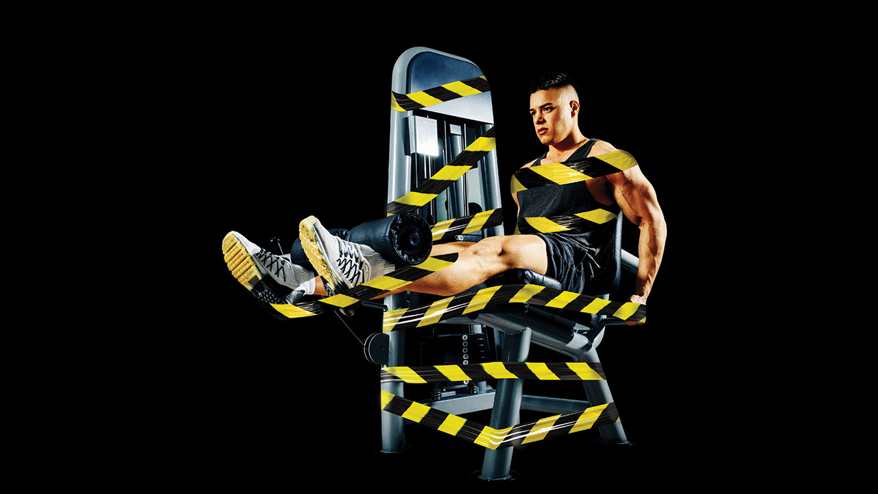 muscular man on a leg extension machine with safety tape wrapped around them