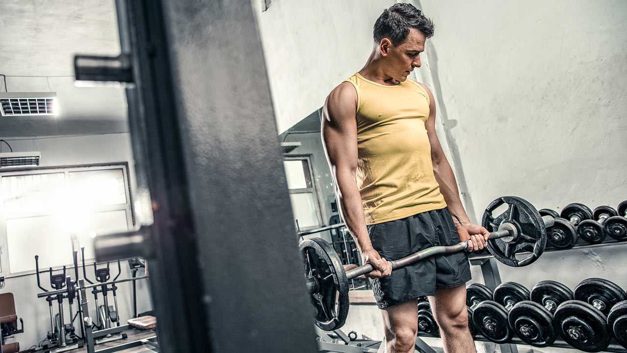 muscular man in the gym with an ez bar