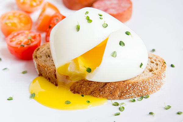 split poached egg on toast with tomatoes