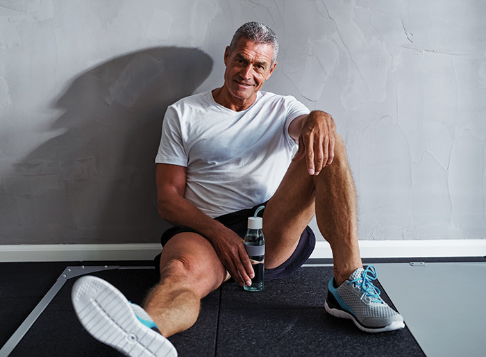 middle aged man sitting on the floor up against a wall