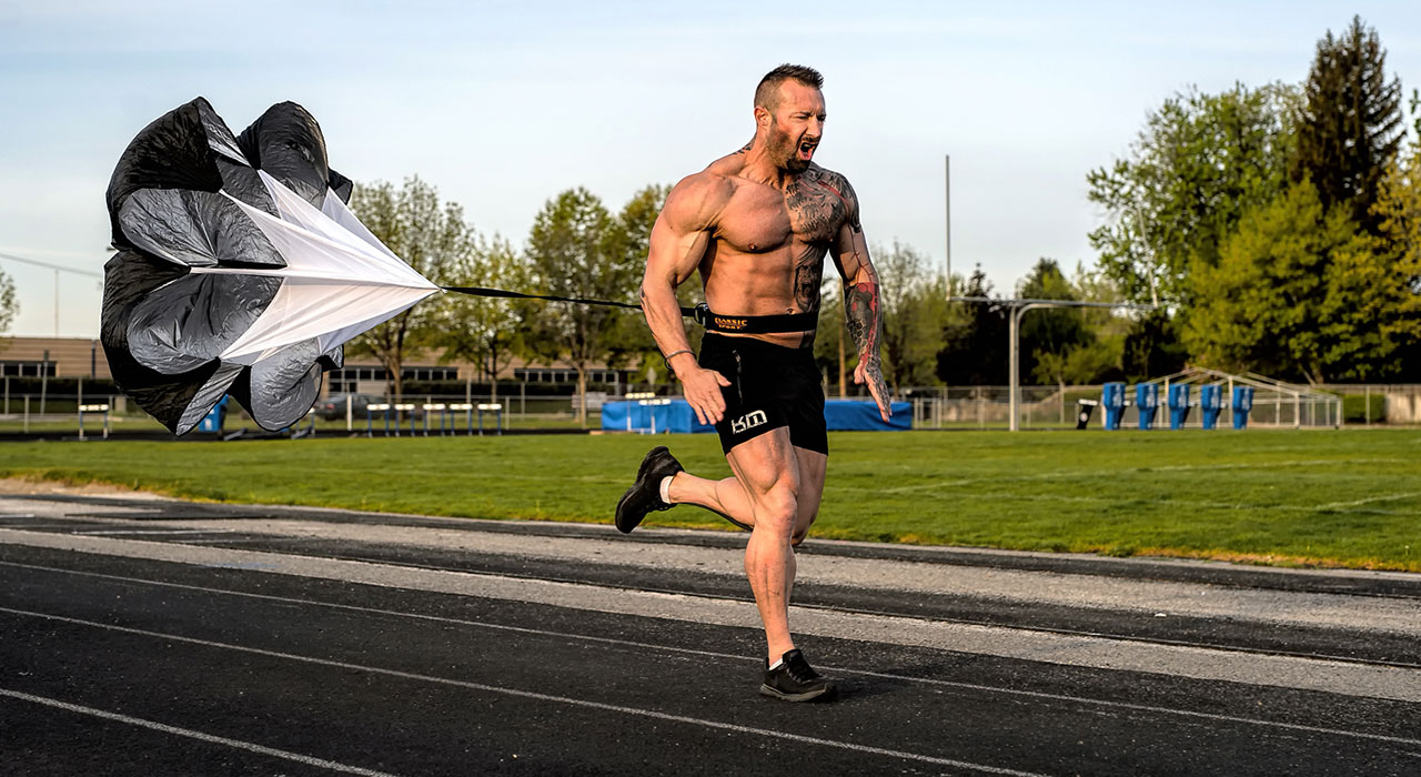 kris gethin running down an athletics track with parachute resistance