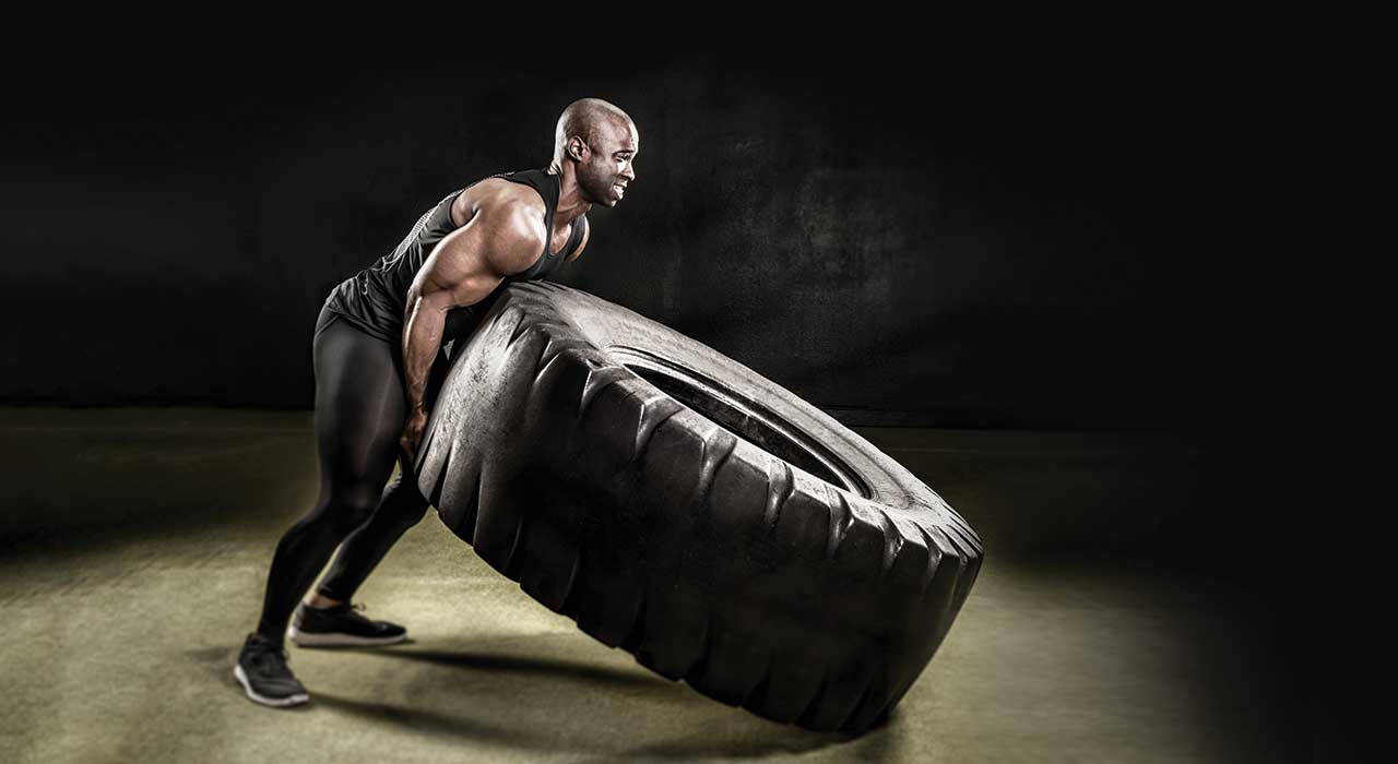 man lifting up a tractor tire
