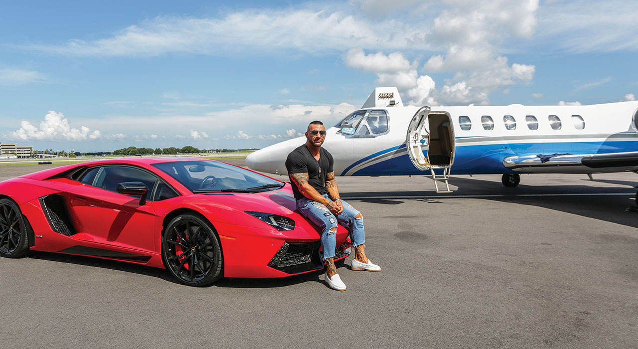 chris cavallini sitting on a sports car next to a private jet