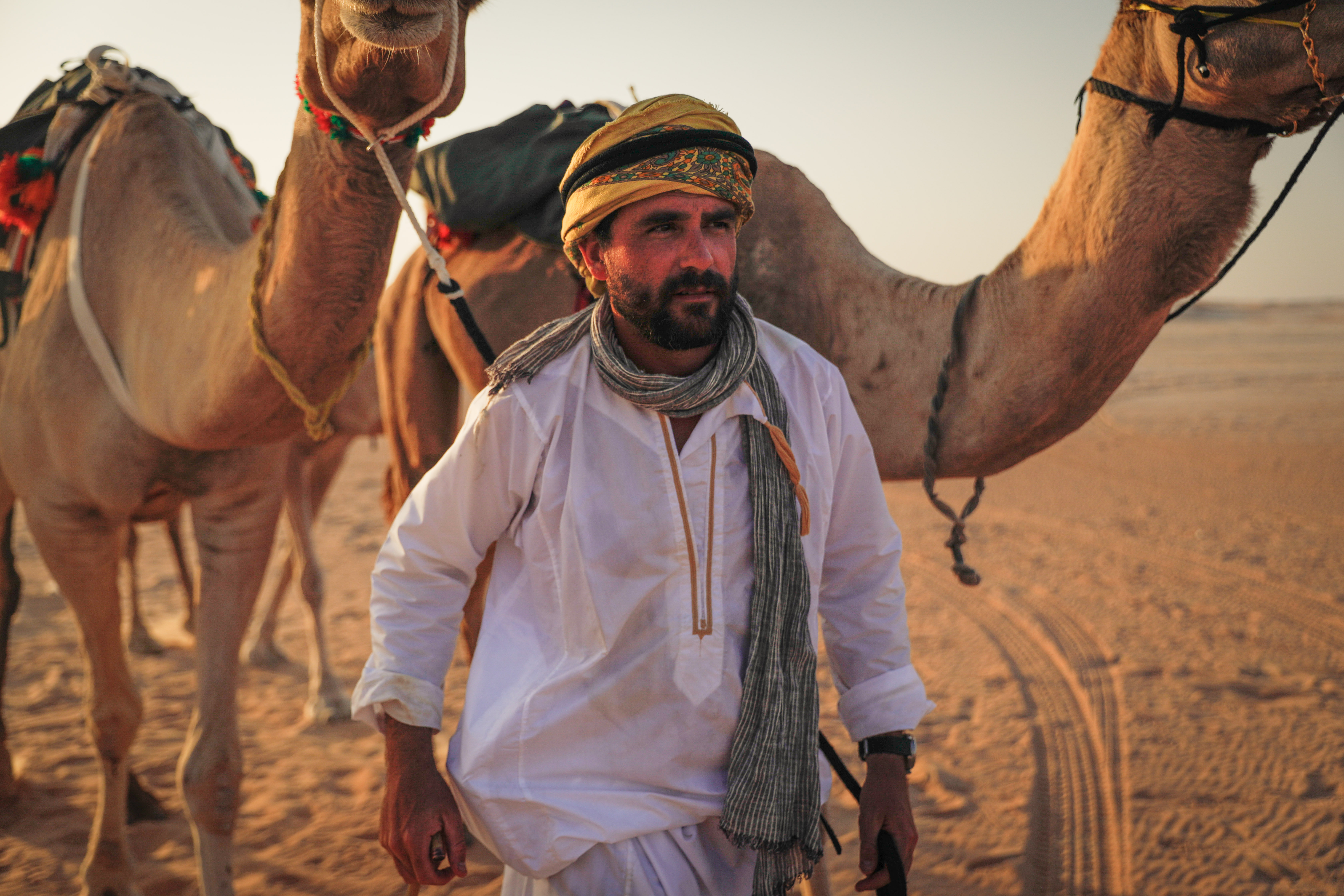 levison wood in arabia next to two camels
