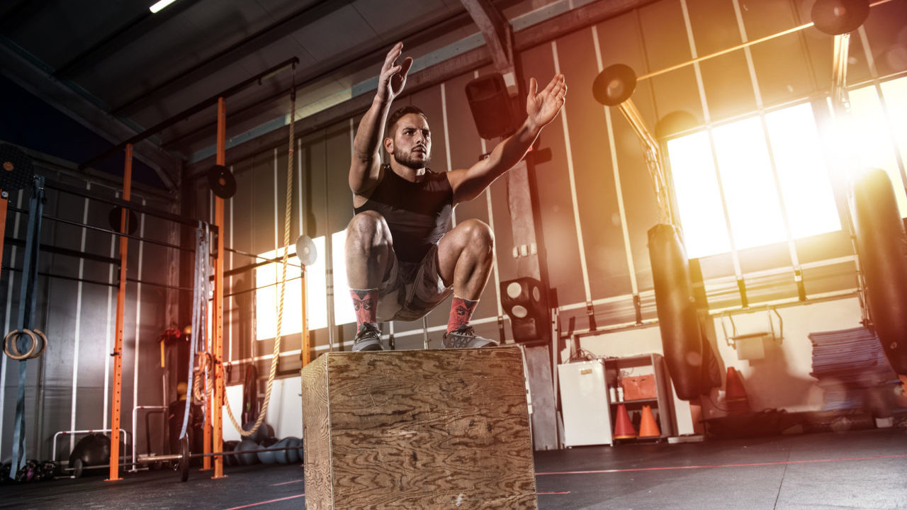 man performing box jump in a gym