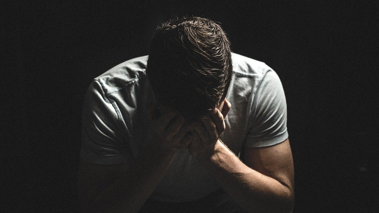 man with head in his hands in dark room