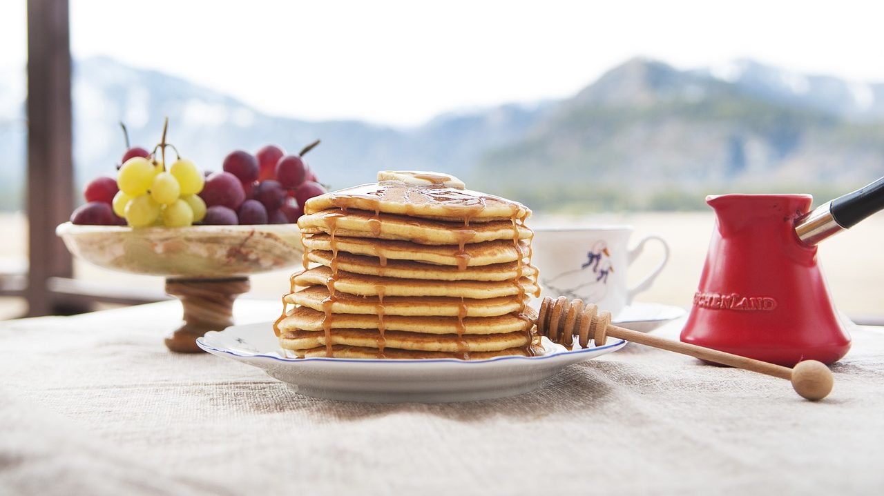 pancakes with honey and butter next to a bunch of grapes
