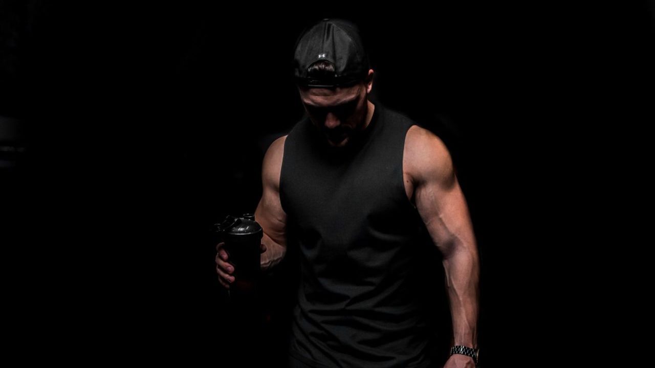 man in black top and shorts with black drinks shaker in hand
