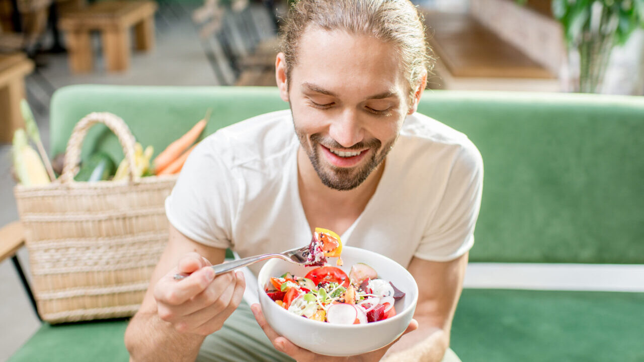 Vegetarian man eating salad indoors